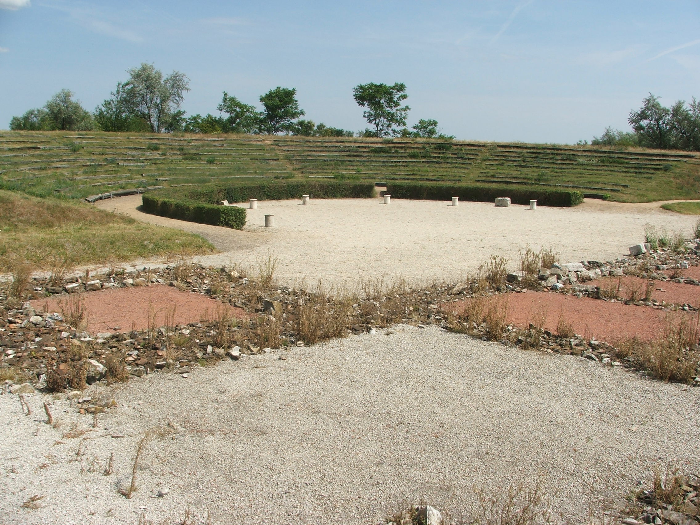Remains of the Roman theatre at Gorsium-Herculia, Tac, with stone seating tiers set into the archaeological park.
