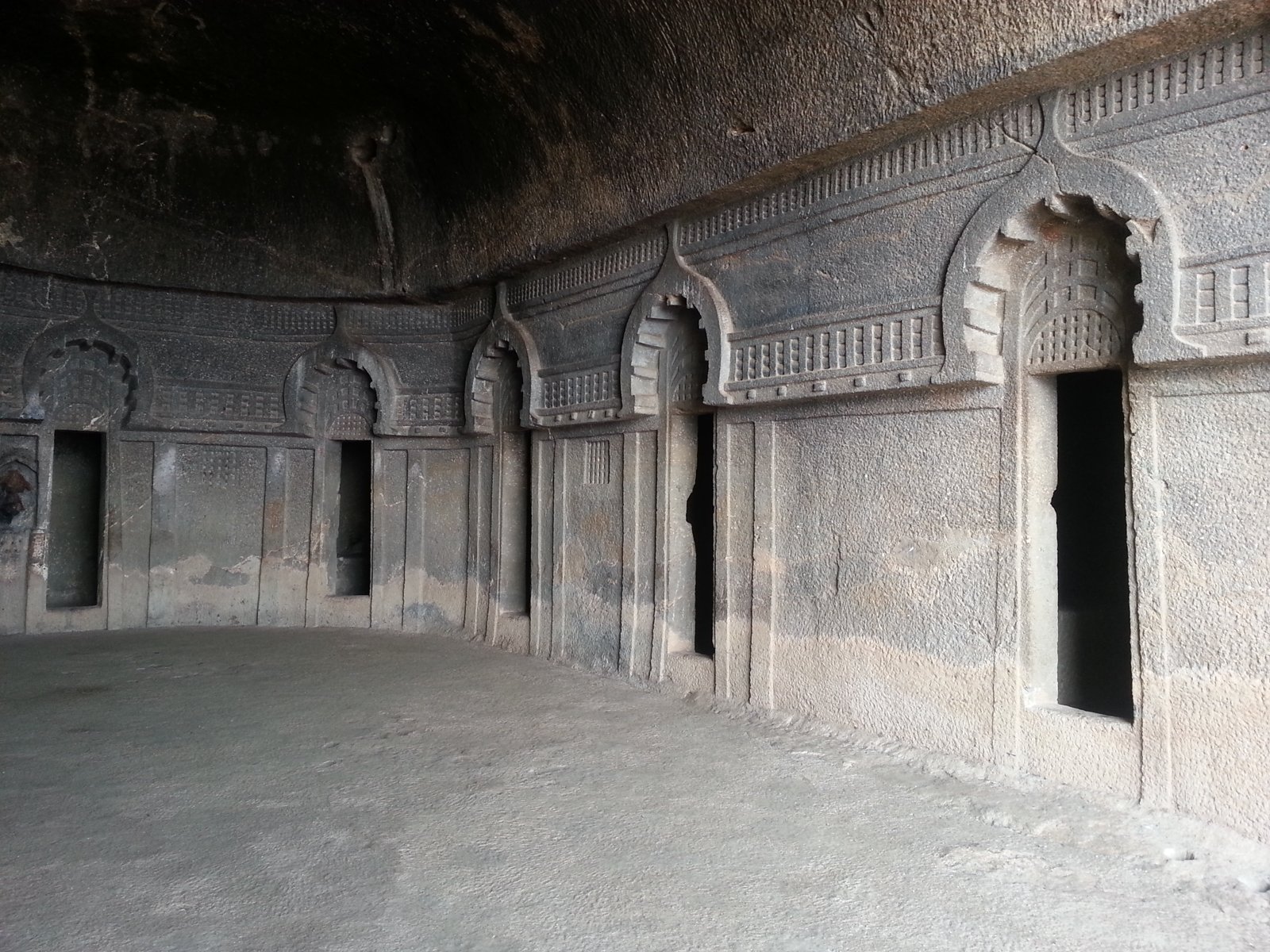 The apsidal vihara, Cave 11, at the Bedse Caves, with cell doorways framed by chaitya-arch reliefs.