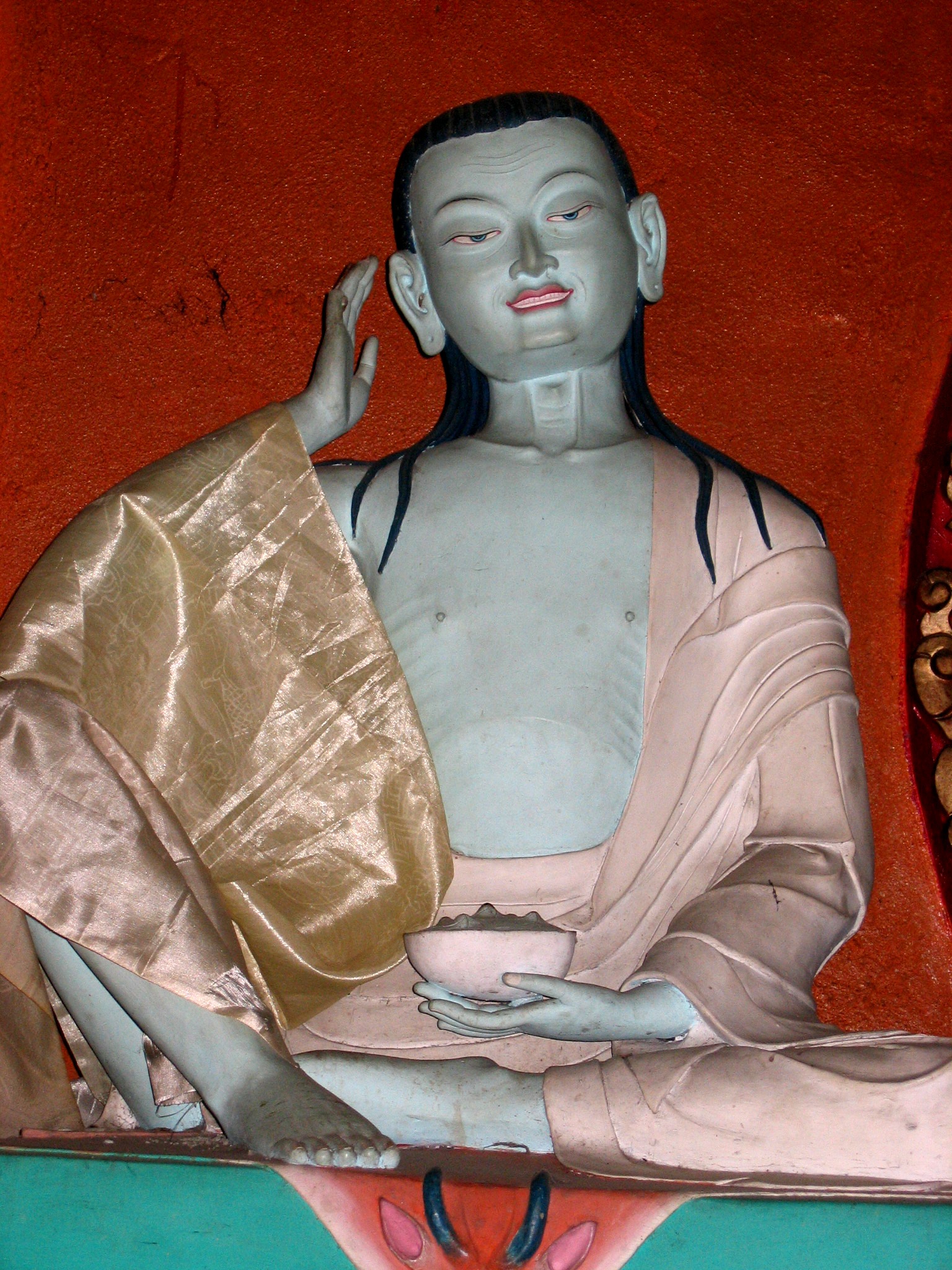 Statue of Milarepa seated in meditation with his right hand raised to his ear